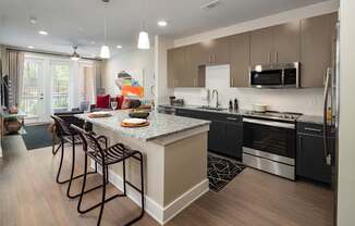 A modern kitchen with granite countertops, neutral two-toned cabinets, and stainless steel appliances.