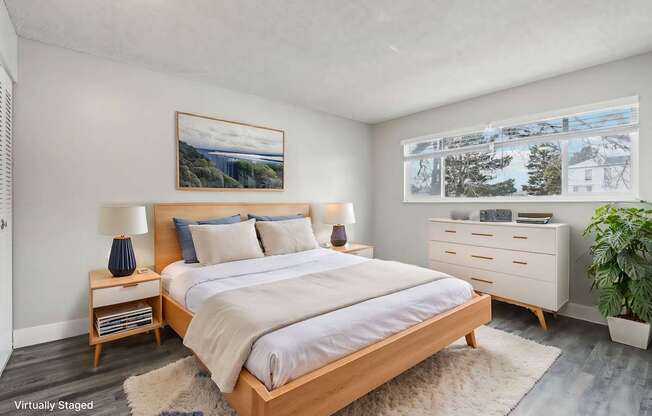 A bedroom with a large bed, a nightstand with a lamp, and a painting on the wall.