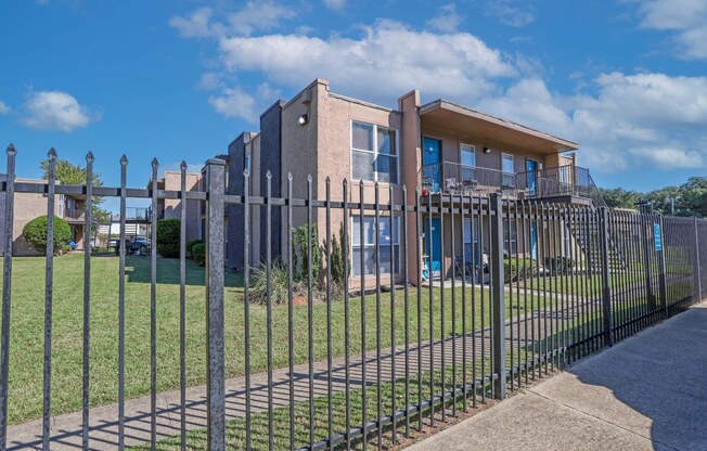 A modern apartment building with a black fence in front at The Drake in Bossier City, LA