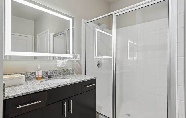 A bathroom with a sink, mirror, and shower.