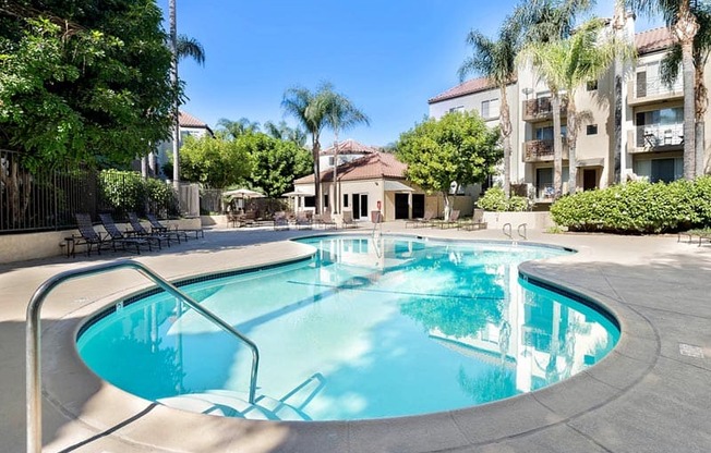 A swimming pool surrounded by palm trees and apartment buildings.