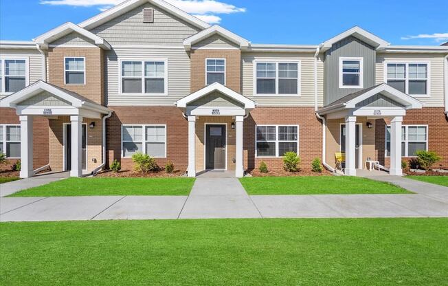 The individual portico entrances and well-kept sidewalk and lawn at Muskego School Apartments