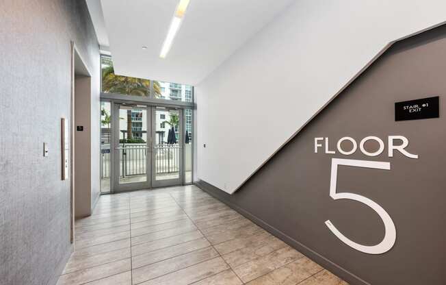 a large hallway with a large floor number on the wall and a glass door in the background