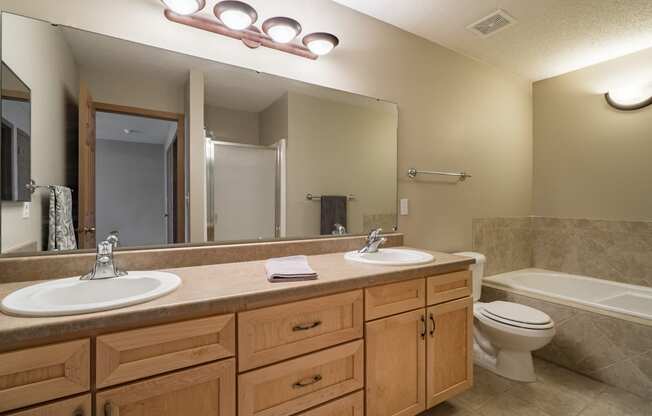 Bathroom with dual sinks and light brown cabinetry at Southwind Villas in Omaha Nebraska