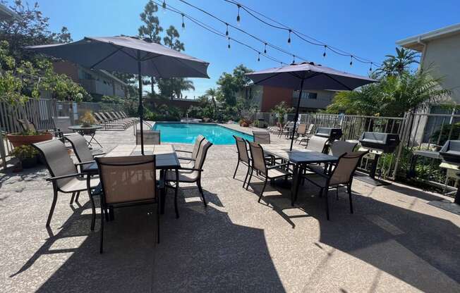 a patio with tables and umbrellas and a swimming pool