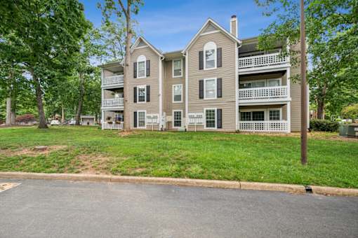 A large apartment building with a green lawn in front.