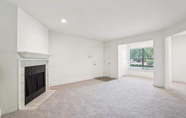 A spacious living room with a fireplace and carpeted floor.