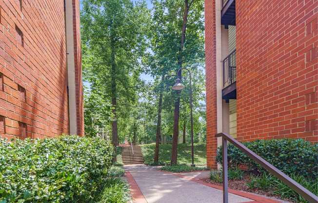 a walkway between two buildings with trees in the background
