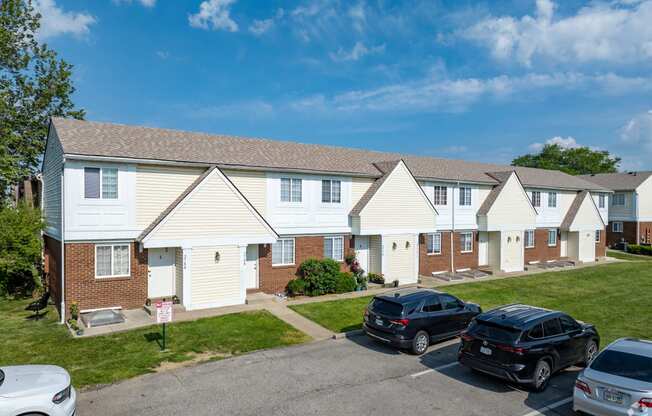 A row of houses with cars parked in front.