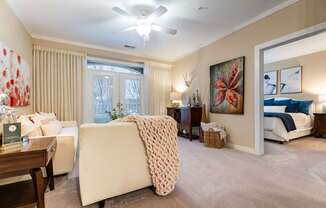 A living room with a white couch and a large painting on the wall.