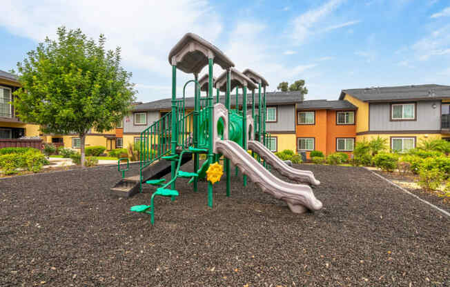 A playground with a green slide and a yellow flower.