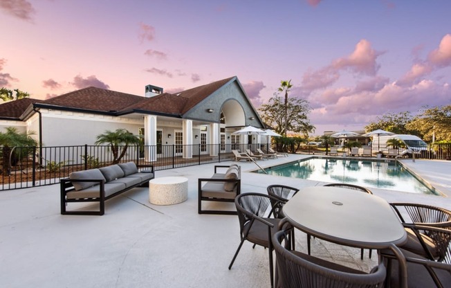 a swimming pool with tables and chairs next to a building