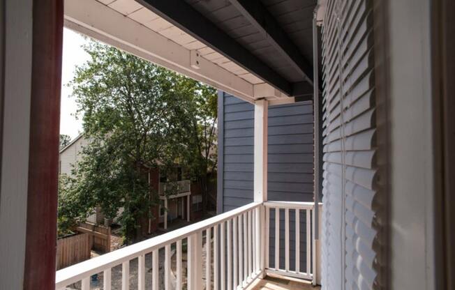 a porch with a white railing and a tree in the background