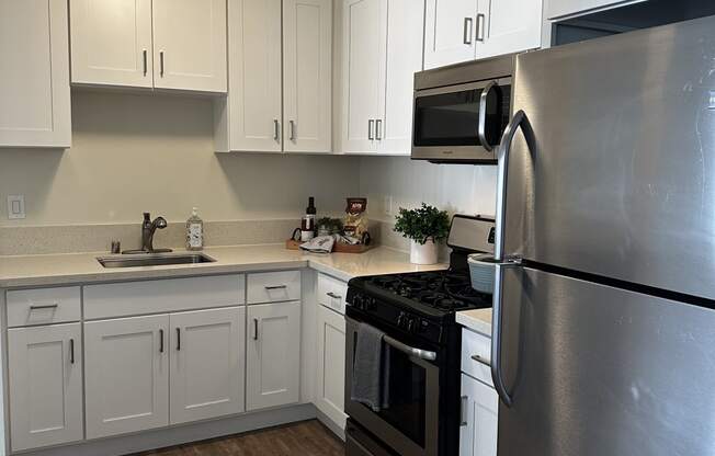 an empty kitchen with stainless steel appliances and white cabinets