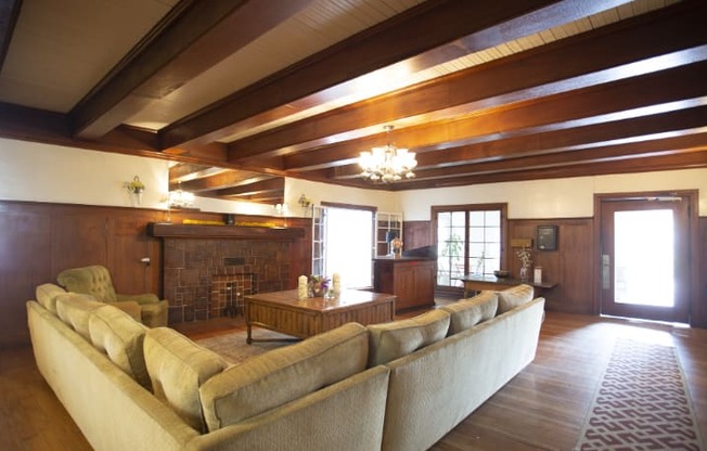 A large beige couch sits in a spacious living room with wooden floors and a fireplace.