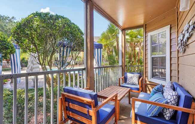 A wooden chair and table are on a porch.