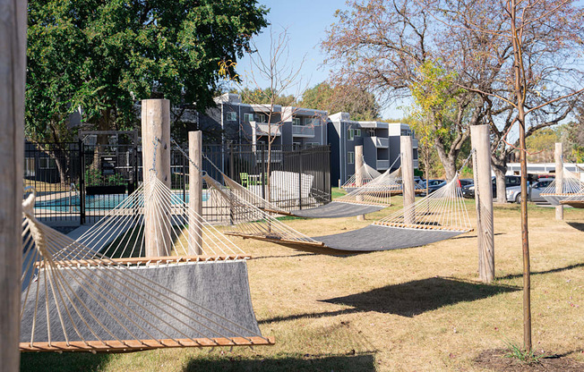 a playground with hammocks and a fence and houses in the background