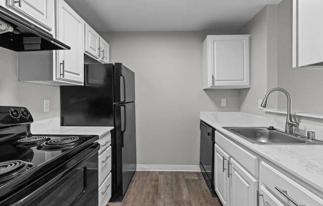 an empty kitchen with white cabinets and black appliances