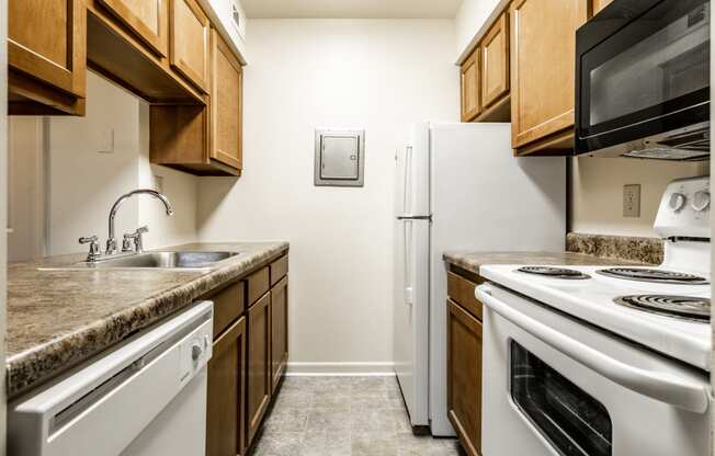 a kitchen with white appliances and wooden cabinets and a counter top at Pheasant Run in Lafayette, IN 47909