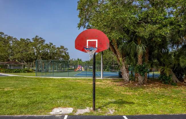 a basketball hoop on a pole in front of a tennis court