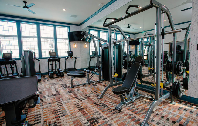 a gym with weights and cardio equipment in a room with windows