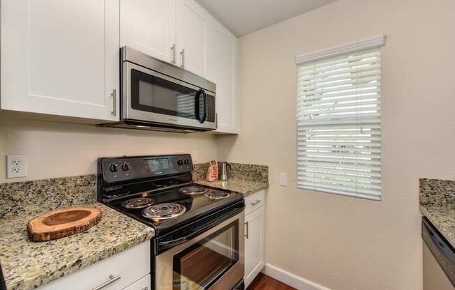 Kitchen with Granite Counters, Hardwood Inspired Floors, Microwave and Oven at Monte Bello Apartments, Sacramento ,95826