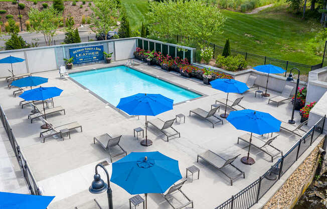 A pool surrounded by blue umbrellas and chairs.
