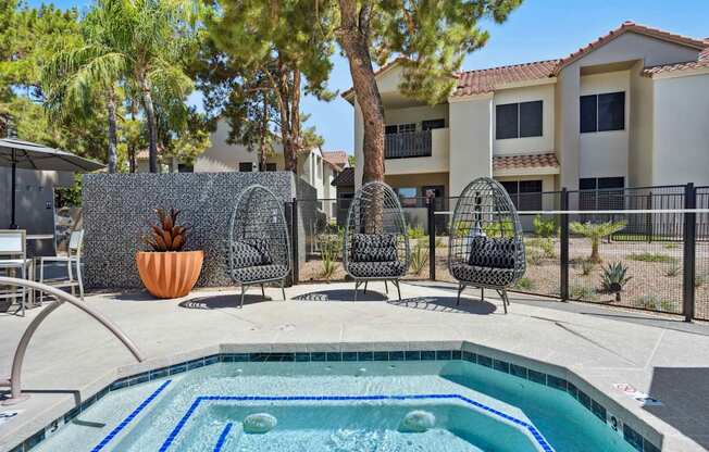 A pool surrounded by chairs and a fence with a wall in the background.