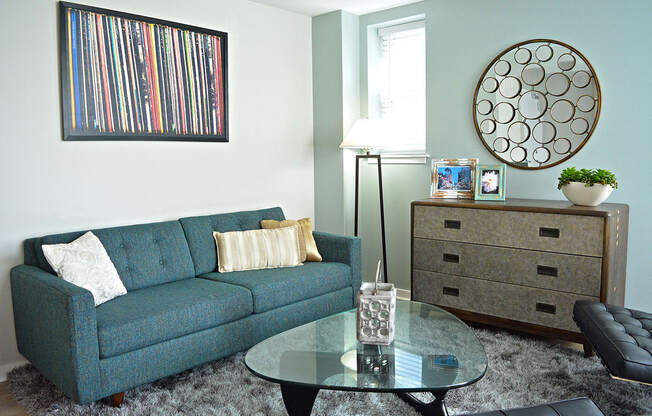 living room with gray rug , blue couch, and wood dresser at Residences at Forest Park, Saint Louis