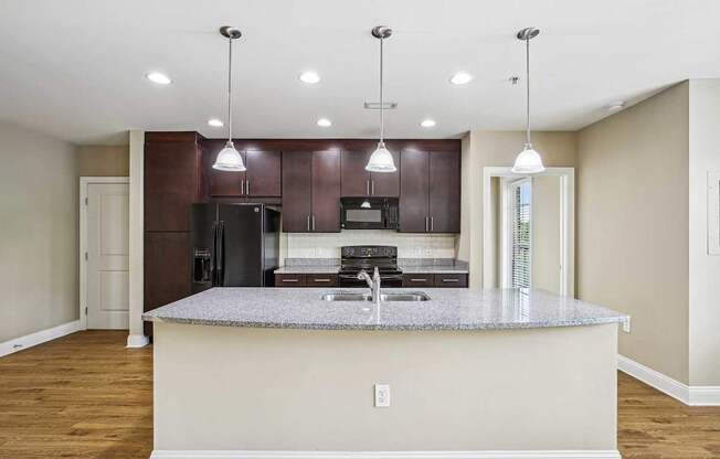 A kitchen with a granite countertop and dark brown cabinets.