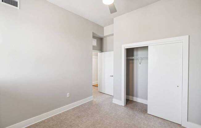 a bedroom with white walls and a closet with a mirrored closet door