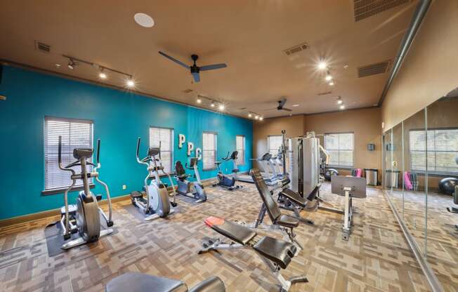 a gym with cardio machines and weights on a wooden floor