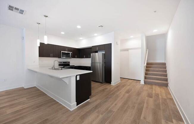 A kitchen with a refrigerator, microwave, and stove top oven.