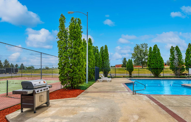 a grill next to a swimming pool with a chain link fence