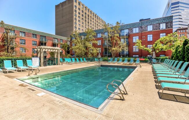 a swimming pool with chairs and a building in the background