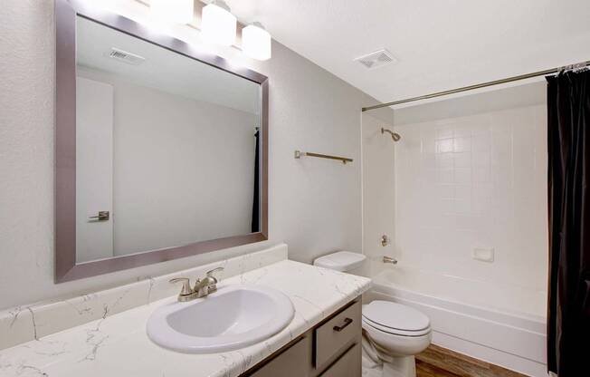 A bathroom with a marble countertop and a white sink.