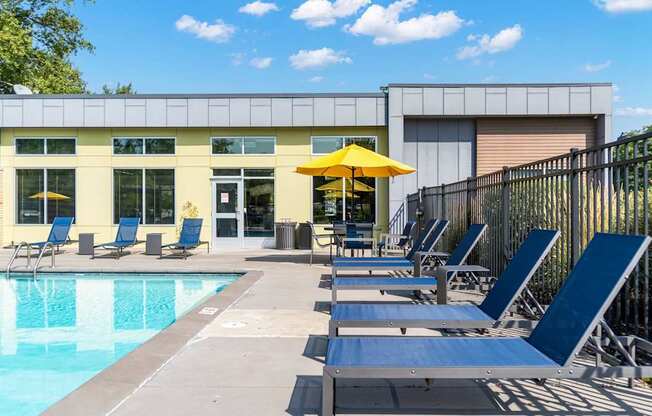 A pool area with sun loungers and a yellow umbrella.
