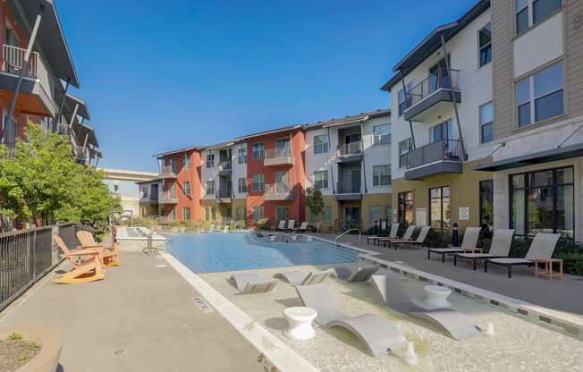 an apartment building with a pool and lounge chairs