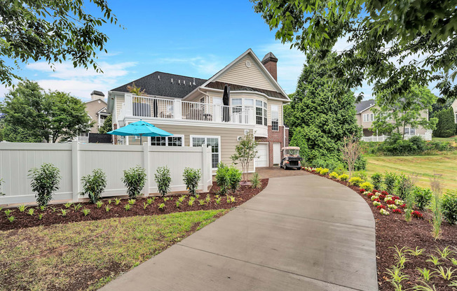 a large white house with a gray roof and a gray sidewalk in front of it