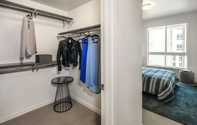 a bedroom with a bed and a closet with clothes rails and a window
