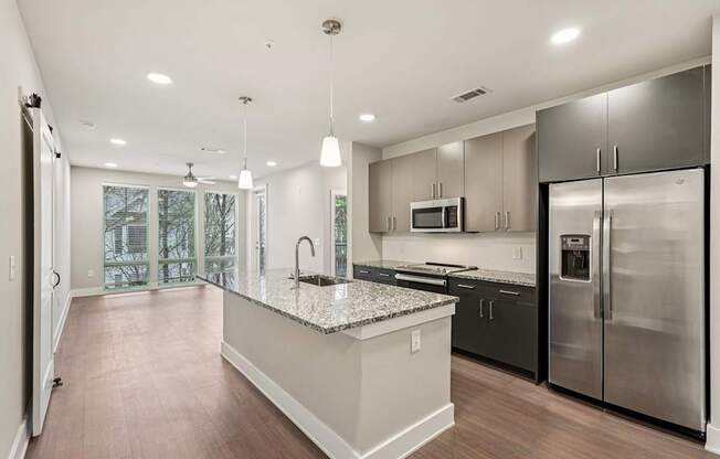 A modern kitchen with a large island and stainless steel appliances, plus floor to ceiling windows .