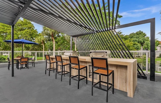 A patio with a bar and chairs under a striped awning.