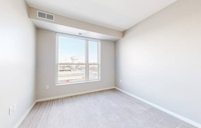 an empty bedroom with large window and white walls
