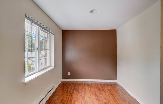 a bedroom with a large window and hardwood floors