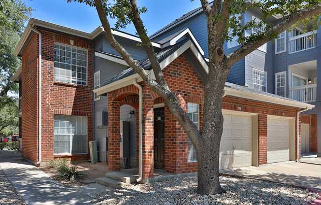 A red brick house with a tree in front.