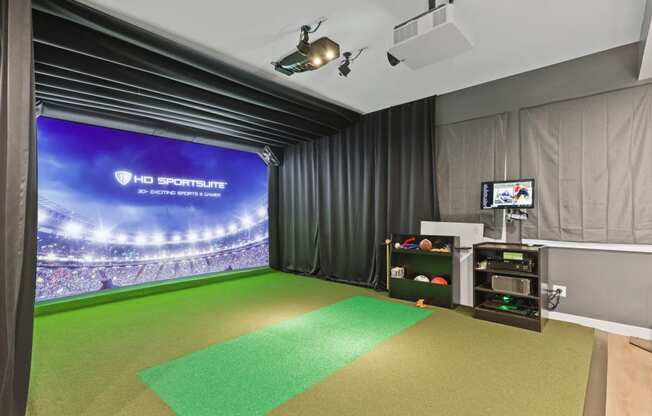 sports simulator room with a green carpet and a projector screen on the wall