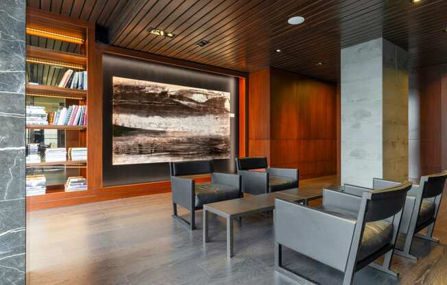 a lounge area with chairs and tables and a painting on the wall