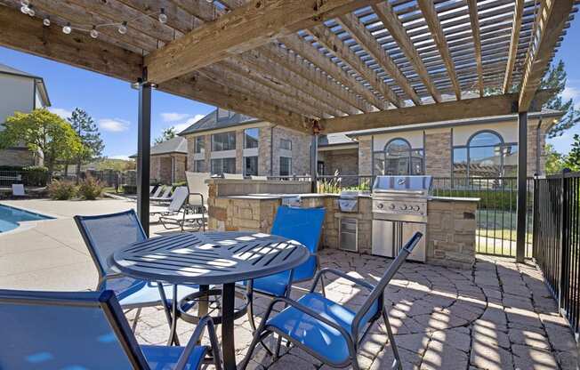 a patio with a pergola and a barbecue grill next to a pool