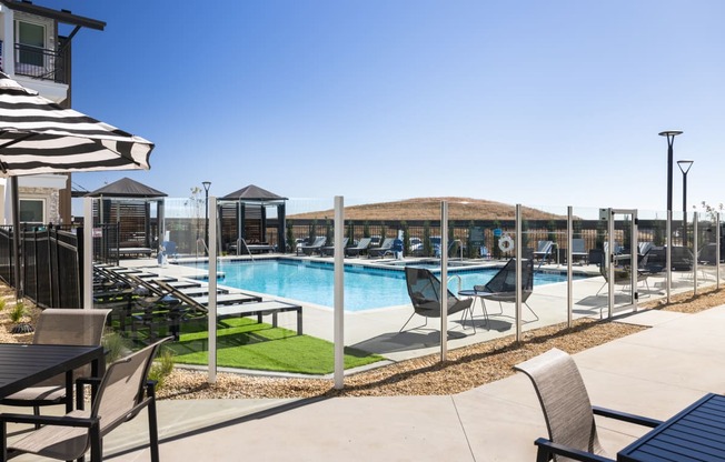a pool with lounge chairs and tables at a resort