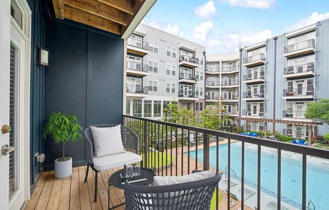 a balcony with chairs and a pool and an apartment building